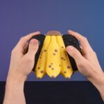 Mando de videojuego forma de banana, fondo azul.