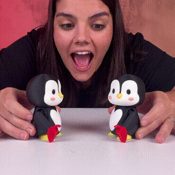 Persona jugando con dos figuras de pingüinos